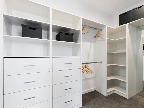 A white closet with many drawers and shelves.